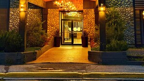 A hotel entrance with a stone facade, a green banner reading "Quality Inn by Choice Hotels," and a wooden overhang above the entrance.