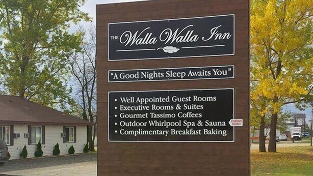 A sign for The Walla Walla Inn with amenities including guest rooms, executive rooms, suites, gourmet Tassimo coffees, an outdoor whirlpool spa, sauna, and complimentary breakfast baking. - The Walla Walla Inn (Rainy River)