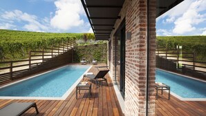 A pool area with two pools, wooden deck, and a vineyard in the background. - Arborina Relais (La Morra)