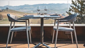 A table with two chairs on a wooden deck, overlooking a scenic landscape. - Arborina Relais (La Morra)