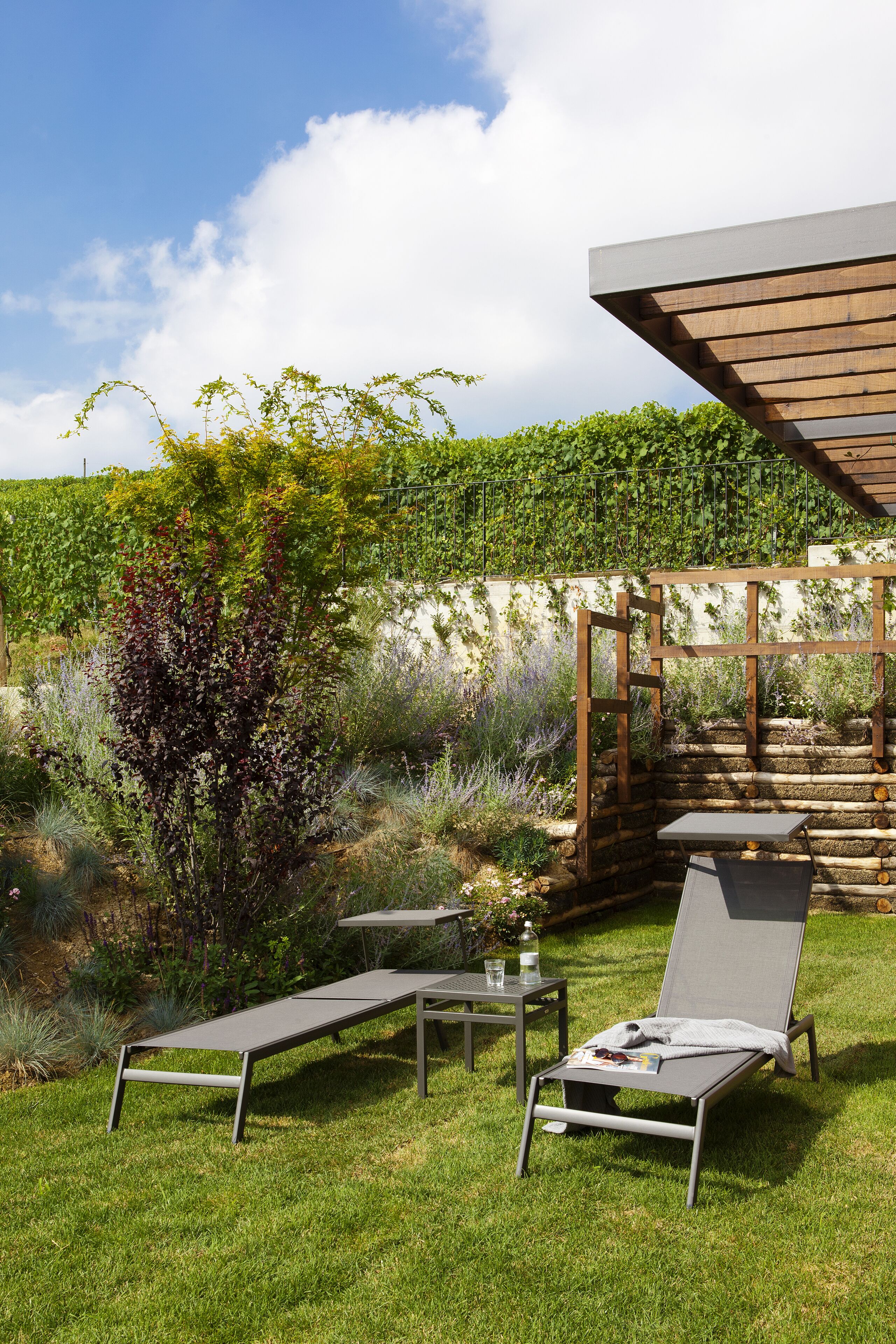 Une terrasse avec deux chaises longues, une petite table et une structure en forme de pergola.