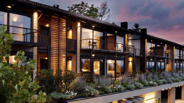 A modern multi-story building with a flat roof, large windows, and a well-lit exterior. - Arborina Relais (La Morra)