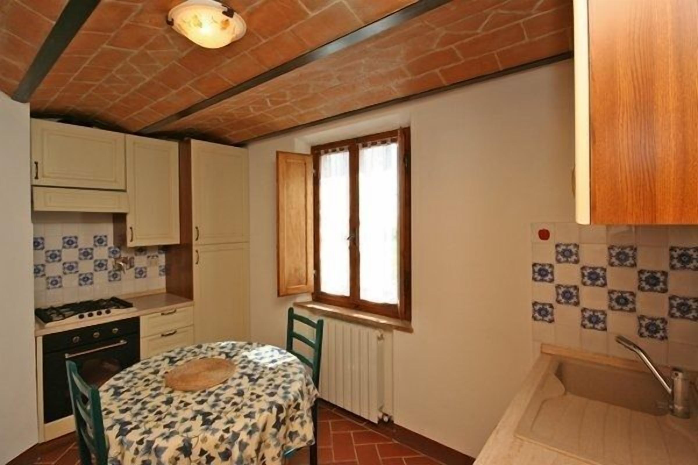 A compact kitchen with a stove, oven, and a window with curtains.