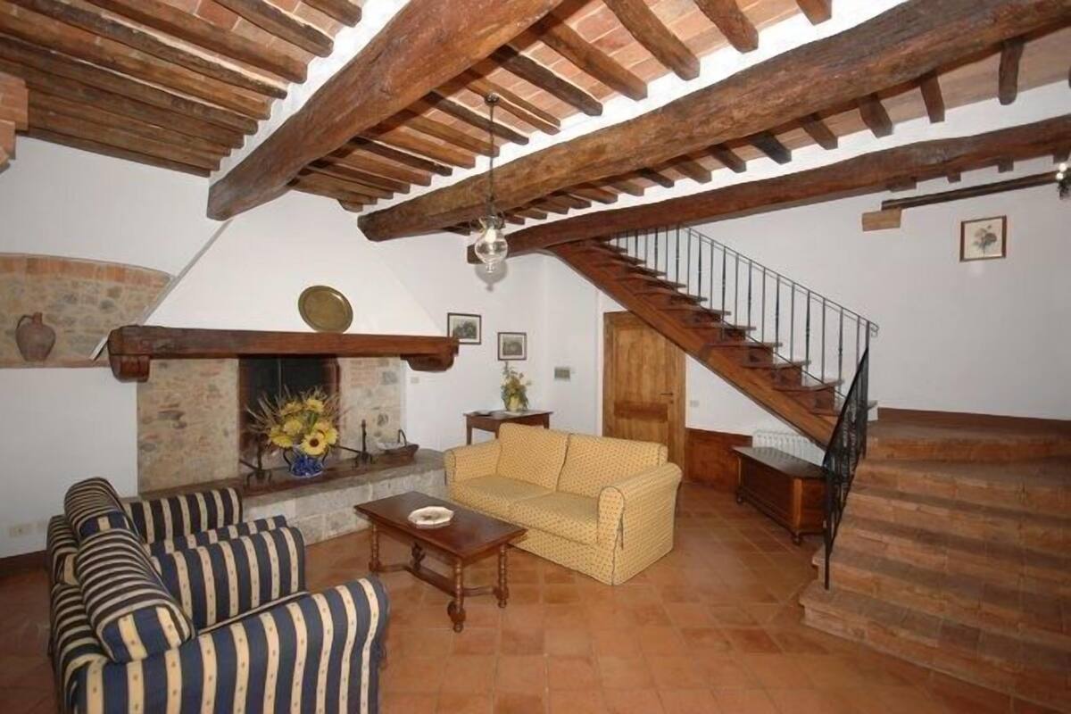 Uma sala de estar ampla com lareira, sofá listrado e escada.