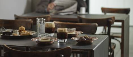 Una mesa de comedor con platos de comida, vasos y una taza de café.