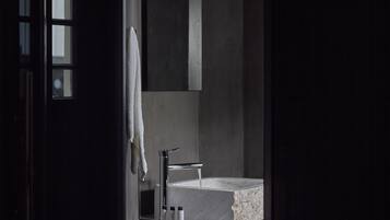 A modern bathroom with a marble sink, a towel hanging on the wall, and toiletries on the counter.