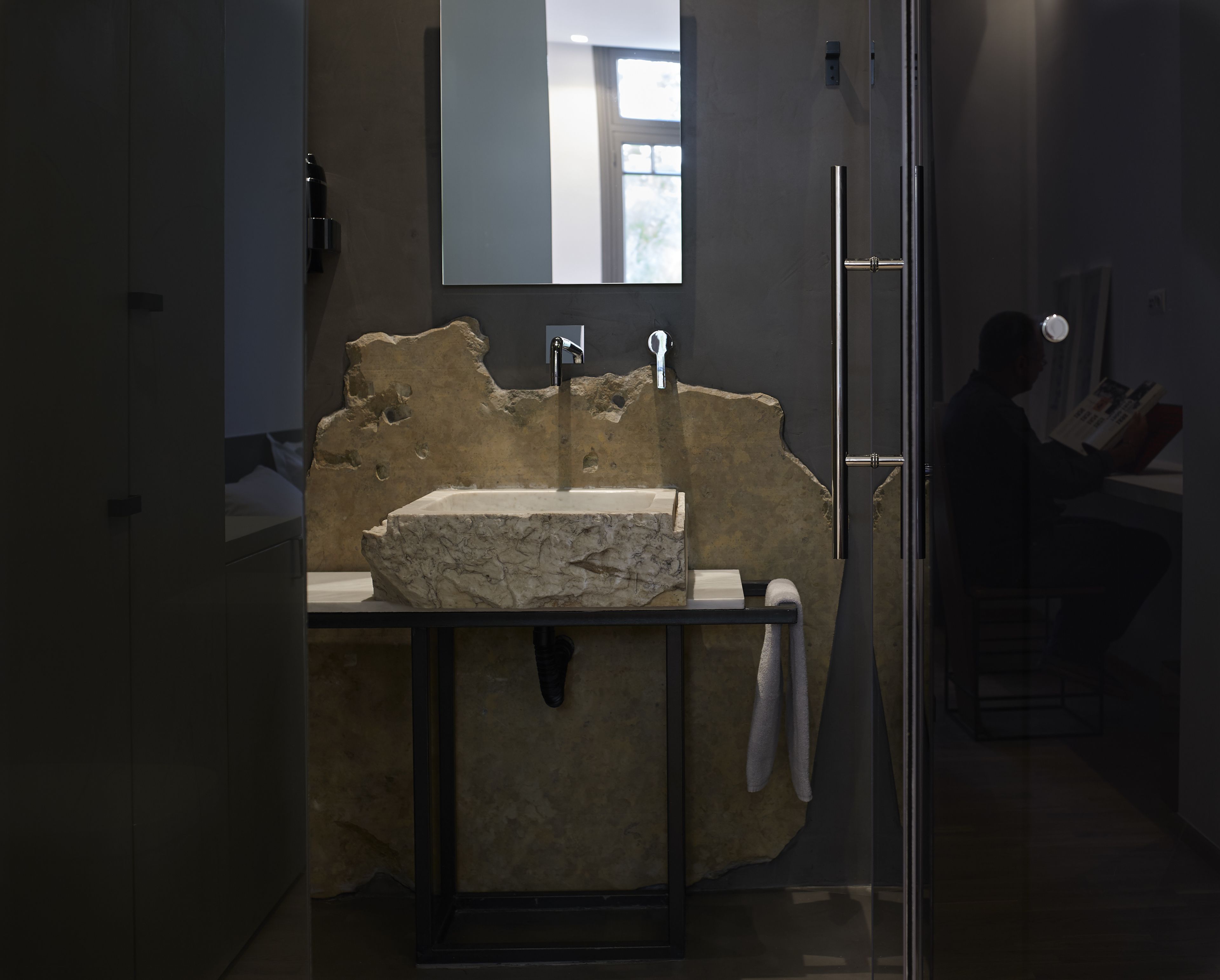 A bathroom with a stone sink, a mirror, and a towel rack.