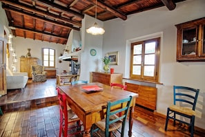 A dining area with a wooden table and chairs, a wooden ceiling, and a window with a view.