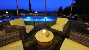 Zona de piscina con muebles de mimbre y una mesa con una vela.