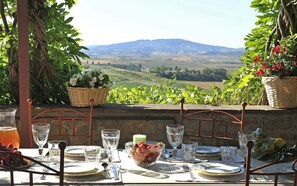 A table set for a meal with a view of rolling hills and a distant mountain range.