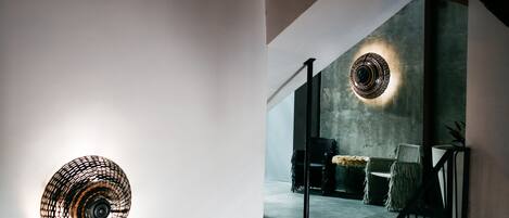 A modern interior with a staircase, a wall-mounted light fixture, and a seating area with a round table and chairs.