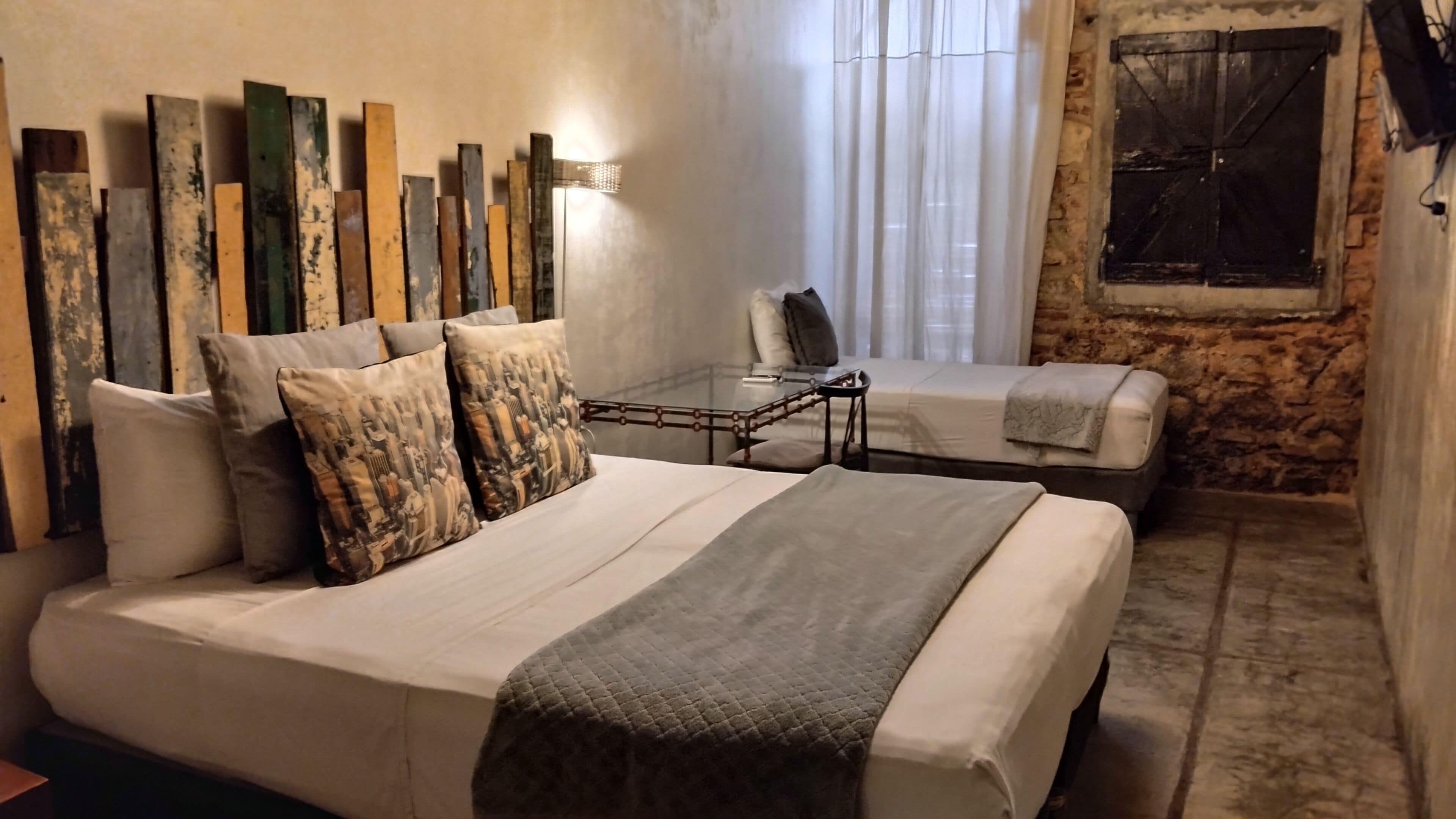Un dormitorio con una cama grande, una cama más pequeña, una mesita de noche y una silla.