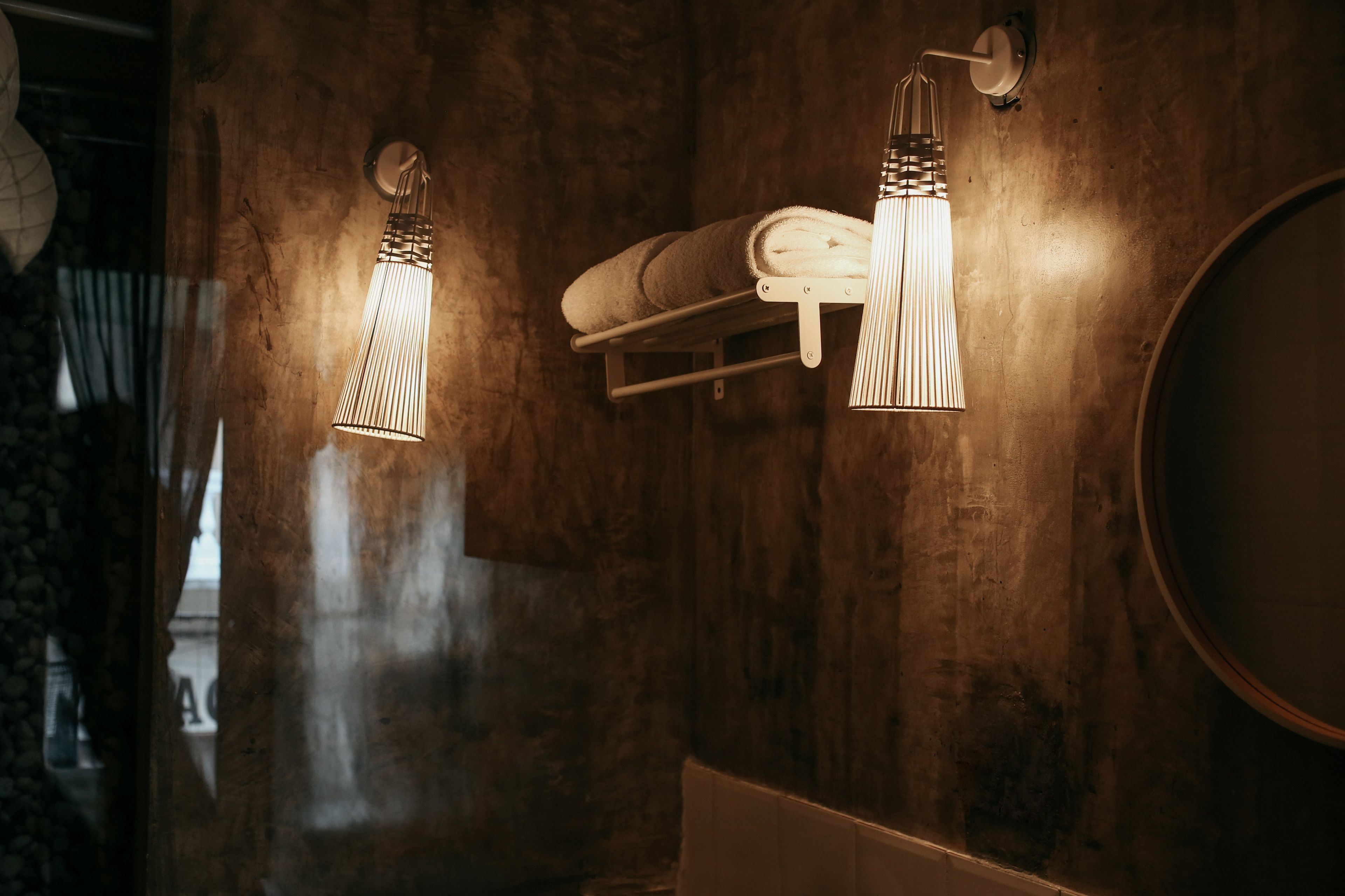 Un bagno con parete in legno, porta asciugamani e specchio tondo.