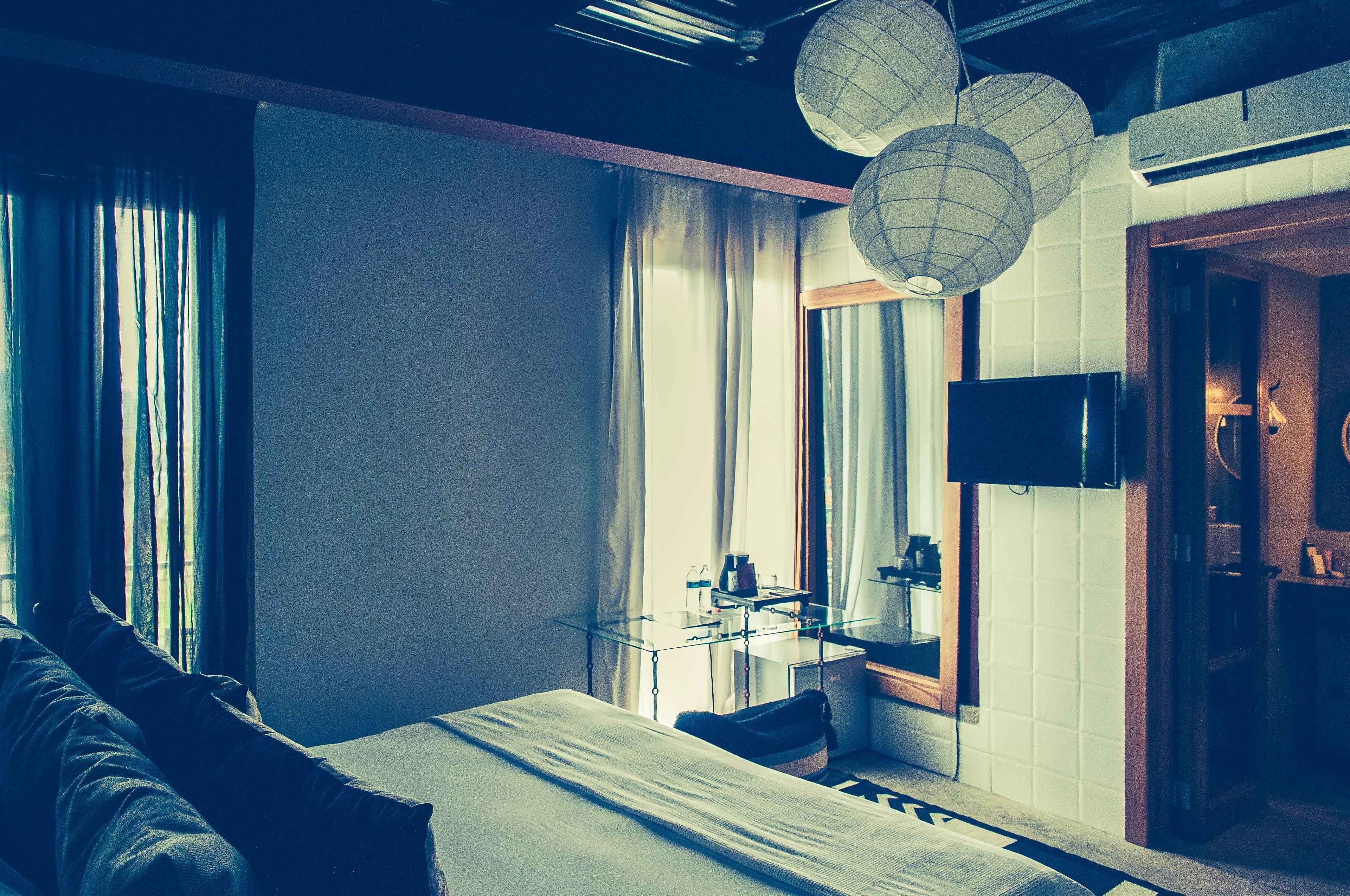 Habitación de hotel con cama, escritorio con espejo, televisión y baño con lavabo e inodoro.