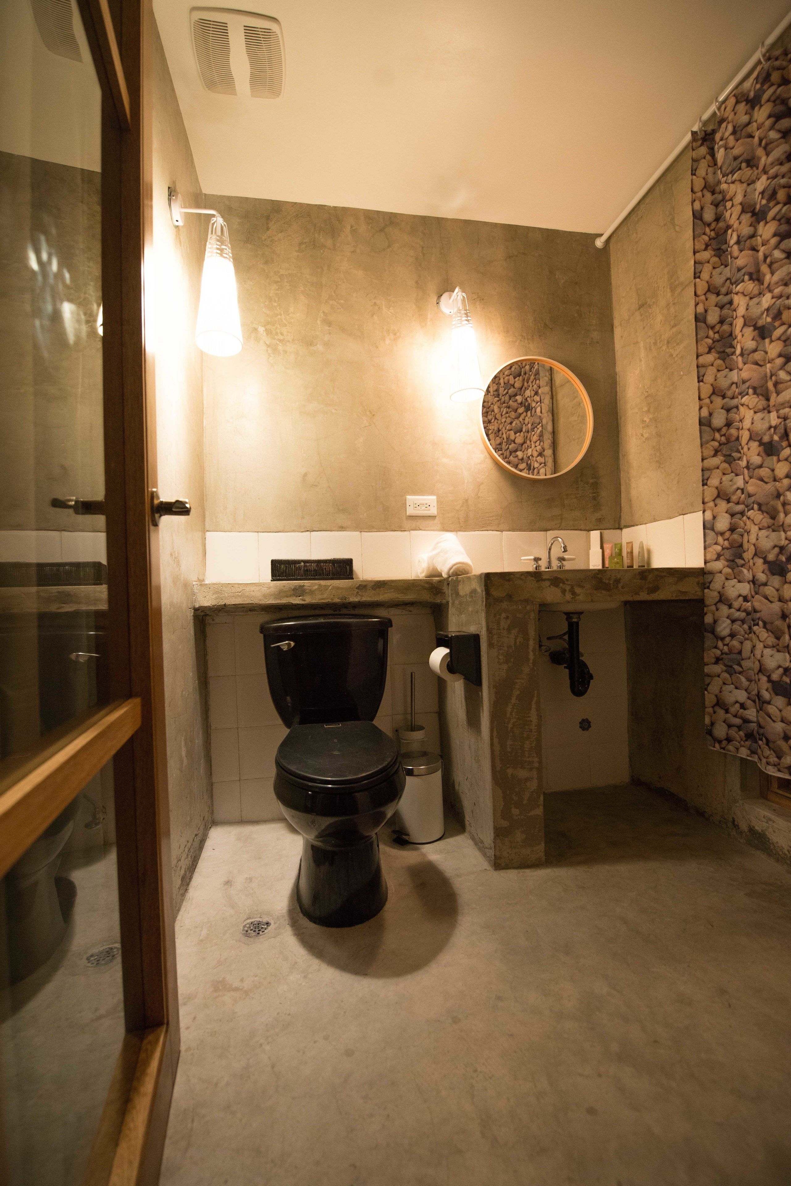 Un baño con inodoro, lavamanos y espejo.
