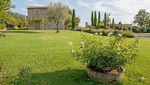A stone building with a tiled roof, surrounded by a well-maintained lawn and flowering plants. - Villa Danilo (San Casciano dei Bagni)