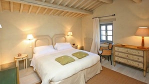 A bedroom with a bed, bedside lamps, a dresser, a chair, and a window. - Villa Danilo (San Casciano dei Bagni)
