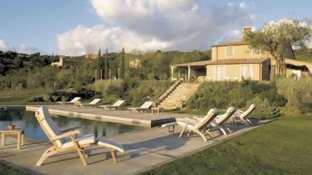 A pool area with lounge chairs and a house in the background. - Villa Danilo (San Casciano dei Bagni)