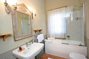Une salle de bain équipée d’un lavabo, d’un miroir, d’une baignoire et d’une douche.