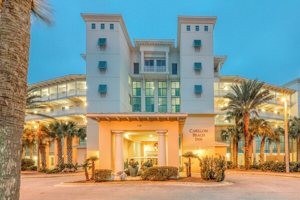 A hotel with a central entrance, multiple balconies, and palm trees. - Carillon Beach Inn (Panama City Beach)