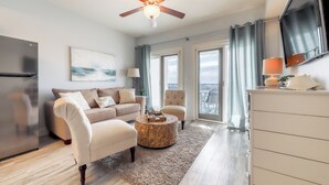 Un salon moderne comprenant un canapé, un fauteuil, une table basse et un ventilateur de plafond.