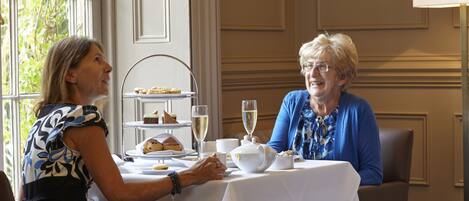 Two people seated at a table with a dessert display and drinks.