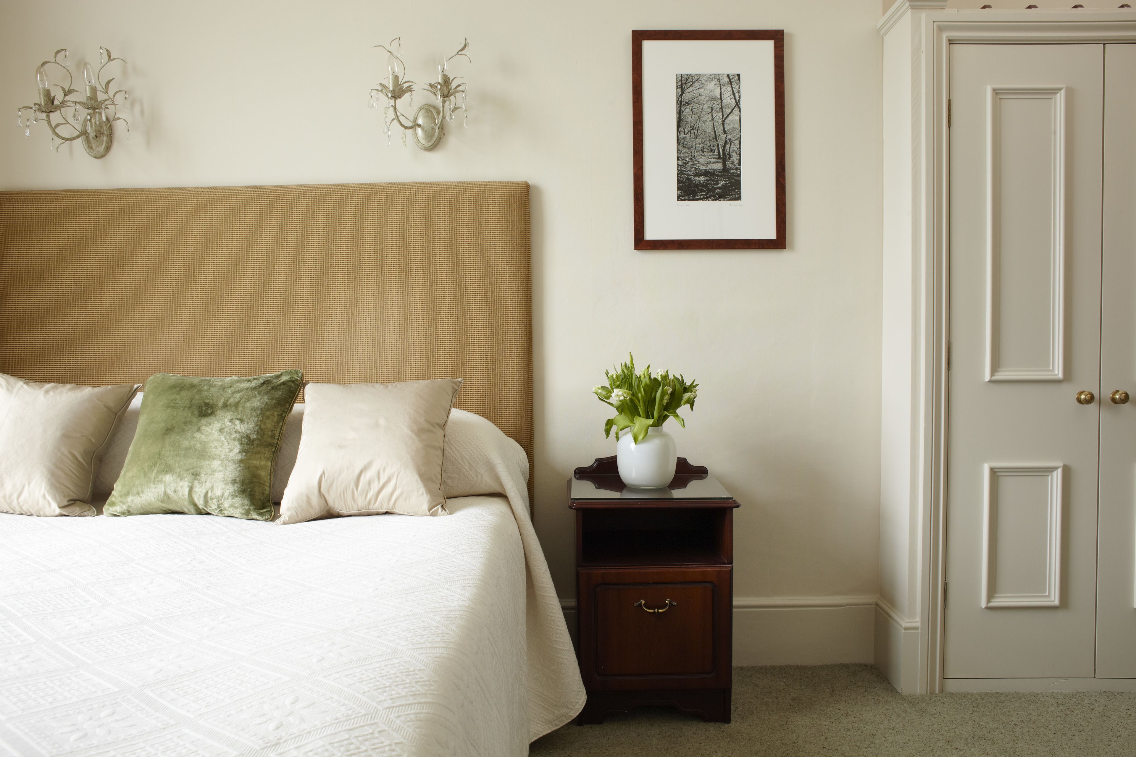A neatly arranged bedroom with a bed, bedside table, and a door.