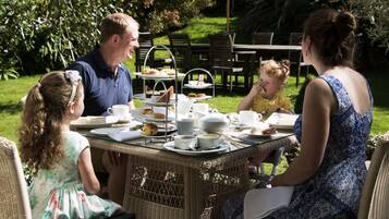 Enjoy meals in a serene outdoor setting surrounded by lush greenery.
