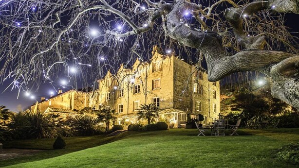 A large, illuminated building with a well-maintained lawn and a prominent tree in the foreground. - The Royal Hotel (Ventnor)