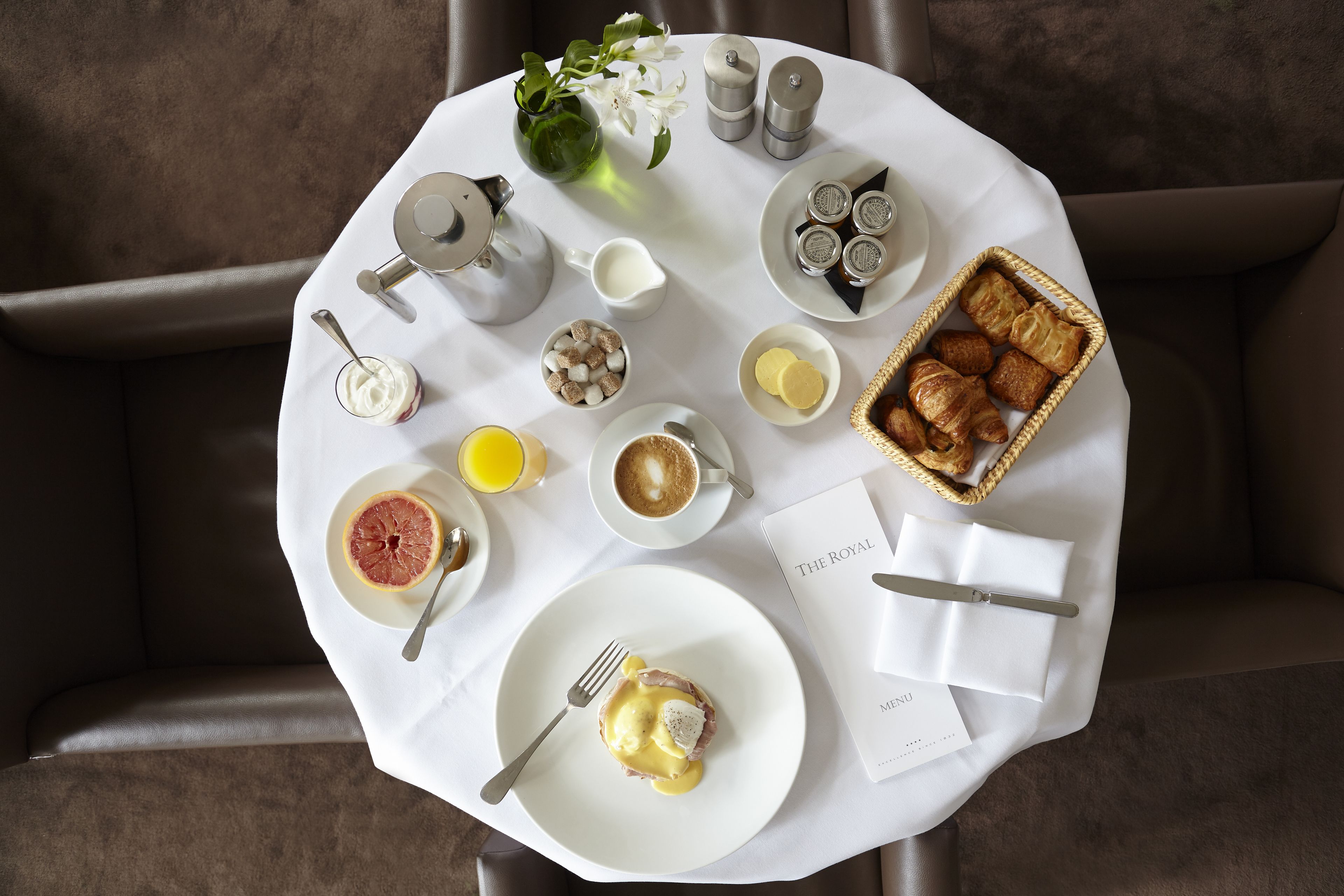 Eixam a l'hora de l'esmorzar, amb estovell blanc, un plat de menjar, una tassa de cafè, un got de suc d'aranja i un menú.