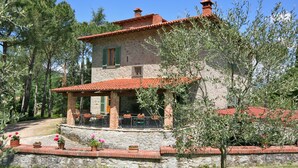 A stone house with a tiled roof, a covered porch, and a stone wall surrounding the property. - Villa Lo Scoiattolo (Subbiano)