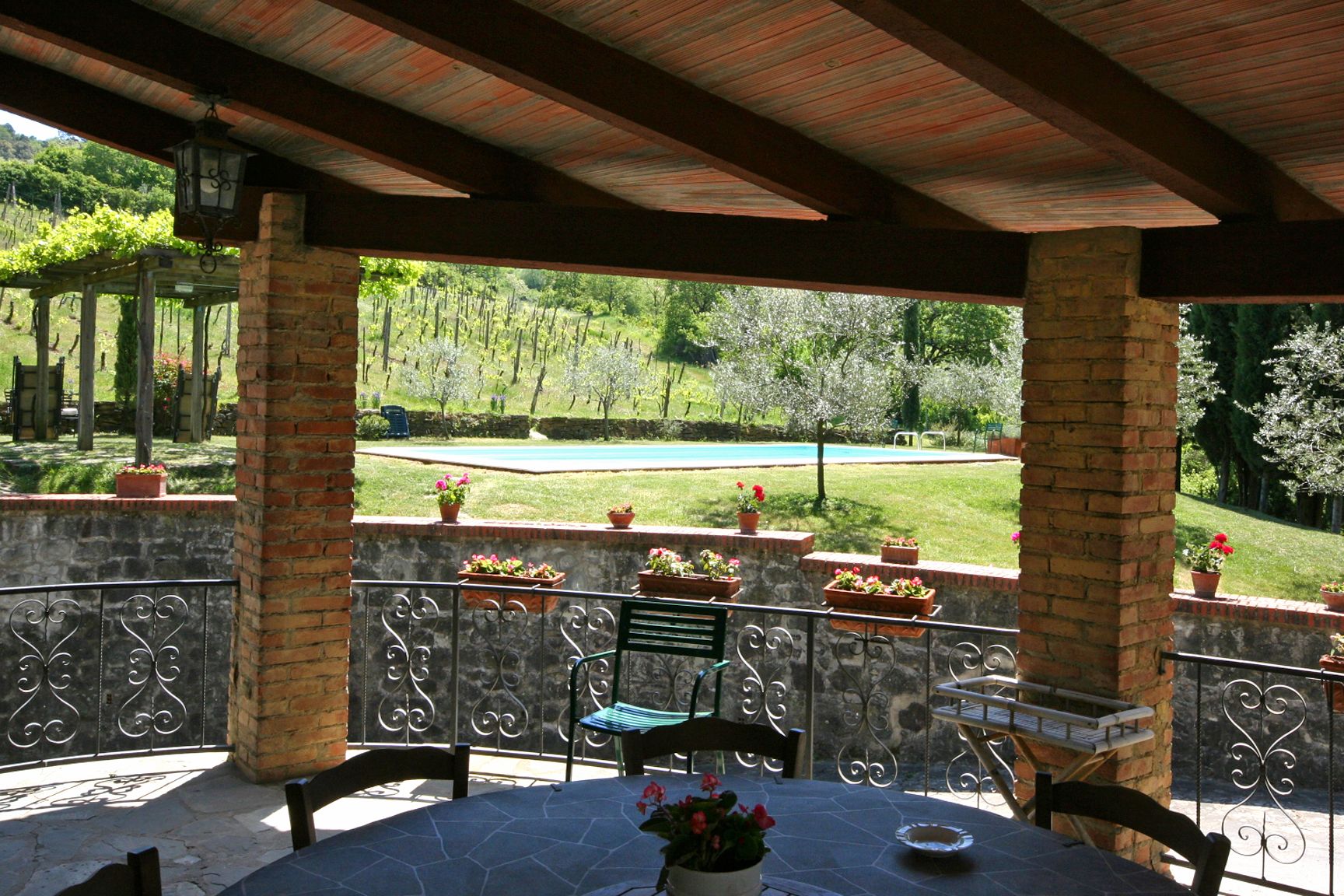 A covered patio with stone flooring, metal railings, and a table with chairs.