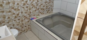 A bathroom with a bathtub, toilet, and tiled walls. - Charlott Hotel (São Paulo)