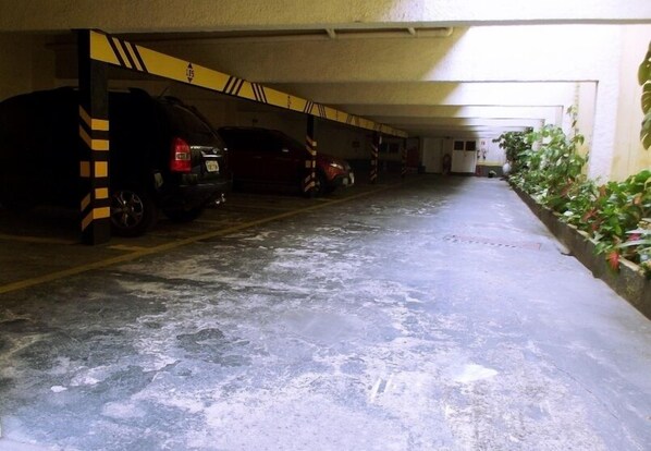 A parking garage with multiple cars parked under a covered area. - Charlott Hotel (São Paulo)