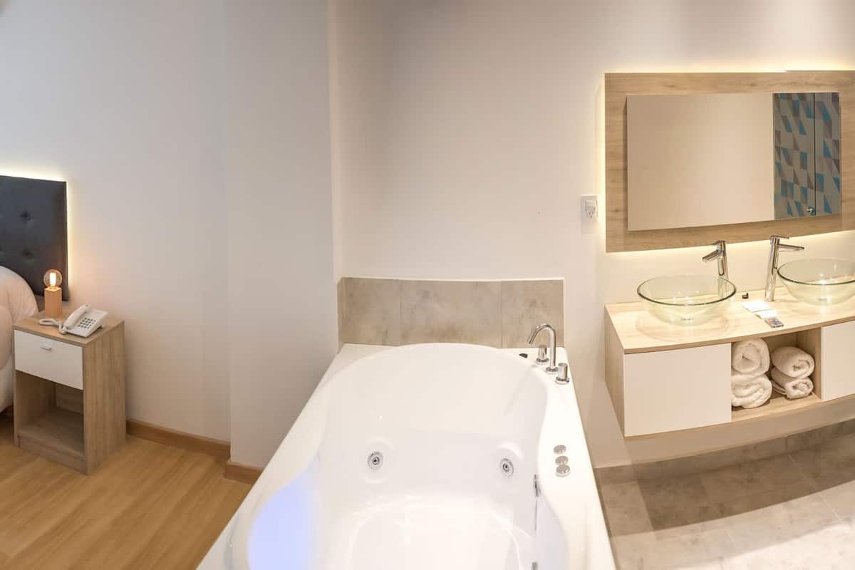 Un dormitorio moderno con cama, mesita de noche y zona de ducha con paredes de vidrio.