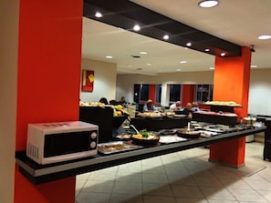 Een buffetopstelling met diverse gerechten en een magnetron.
