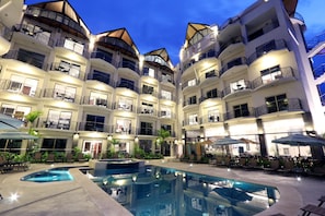 A multi-story hotel with balconies, a swimming pool, and outdoor seating areas. - Luxury Sky Penthouses 3-6BR Condo-Hotel at Oceano Jaco (Jacó)