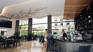A modern bar area with a high ceiling, large windows, and a view of palm trees. - Luxury Sky Penthouses 3-6BR Condo-Hotel at Oceano Jaco (Jacó)