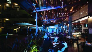 An outdoor dining area with tables and chairs, surrounded by plants and under a canopy. - Luxury Sky Penthouses 3-6BR Condo-Hotel at Oceano Jaco (Jacó)