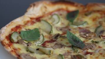 A close-up of a pizza with zucchini, mushrooms, and basil leaves.