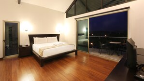 A bedroom with a bed, bedside tables, a TV, and a balcony with a table and chairs. - Luxury Sky Penthouses 3-6BR Condo-Hotel at Oceano Jaco (Jacó)