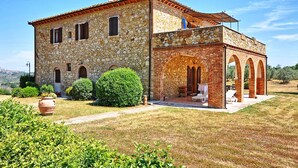 A stone building with a terrace and outdoor seating. - Vittoriana (San Gimignano)