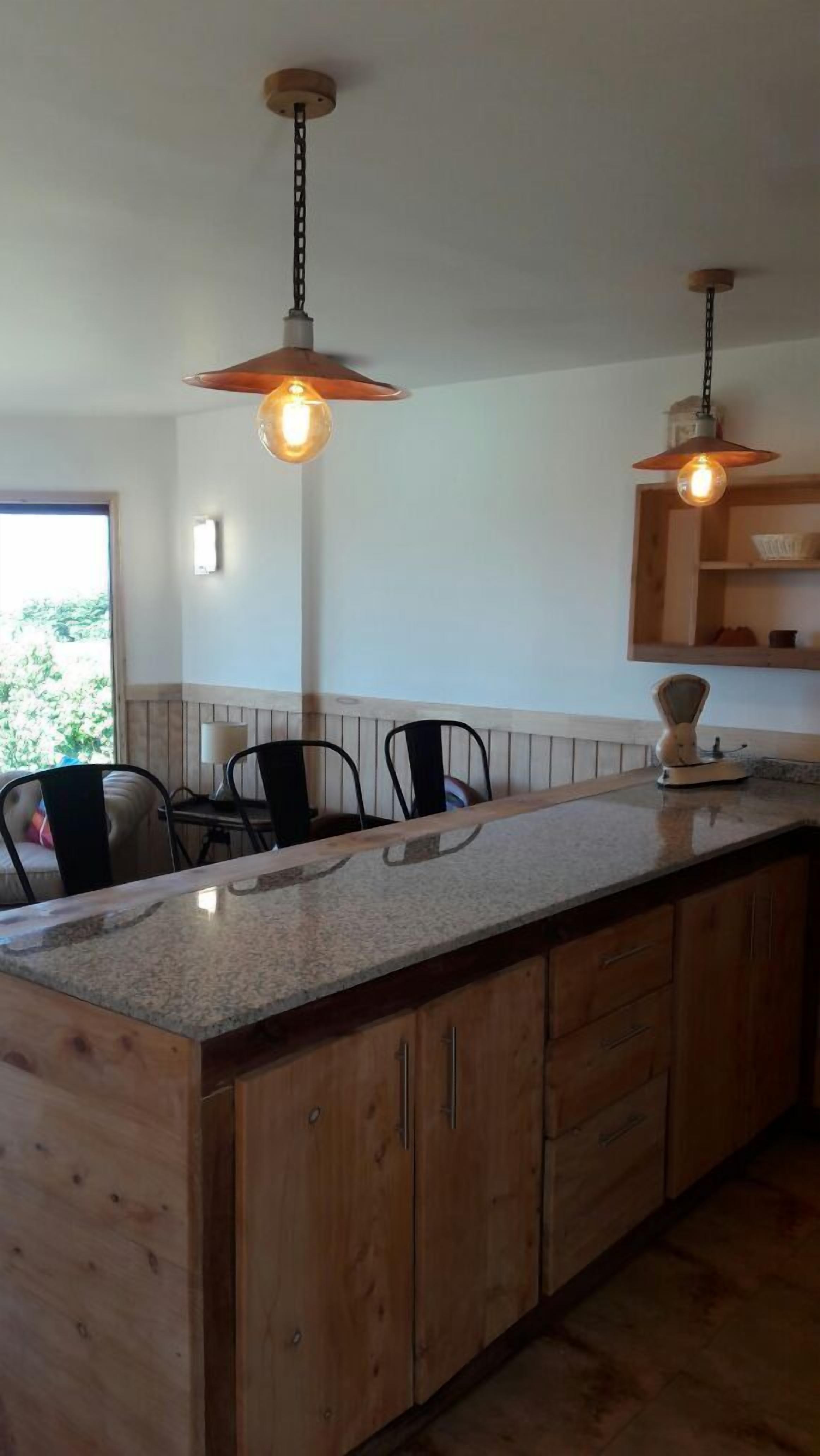 Una cucina con mobili in legno, un piano di lavoro in granito e luci a sospensione.