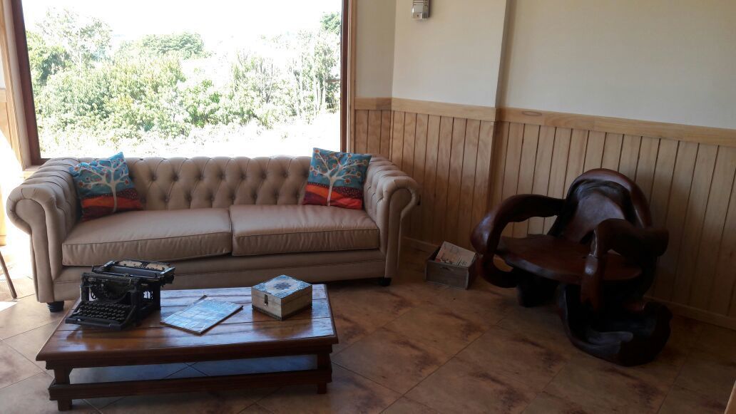 Un salon avec un canapé beige, une table basse en bois, une machine à écrire ancienne et une chaise en bois.
