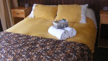 A hotel room with a large bed, two nightstands, a wooden headboard, and a woven throw blanket.