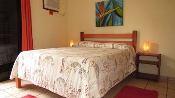 Quarto com cama, duas luminárias de cabeceira, um quadro na parede e uma janela com cortinas.