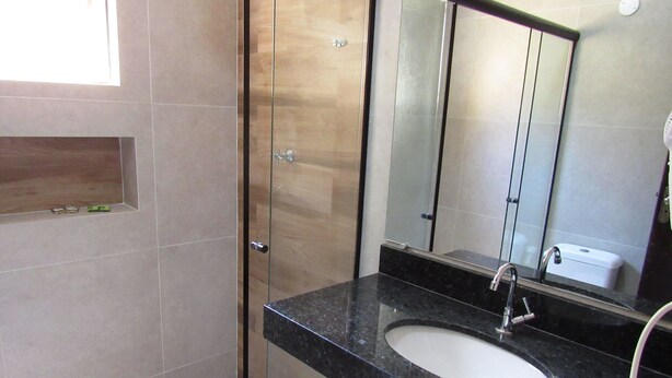 A modern bathroom with a glass shower enclosure, a black marble sink, and a large mirror. - Pousada Casa na Praia (Ubatuba)