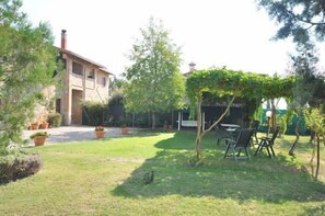 Un patio con un edificio, una pérgola y mesas al aire libre.