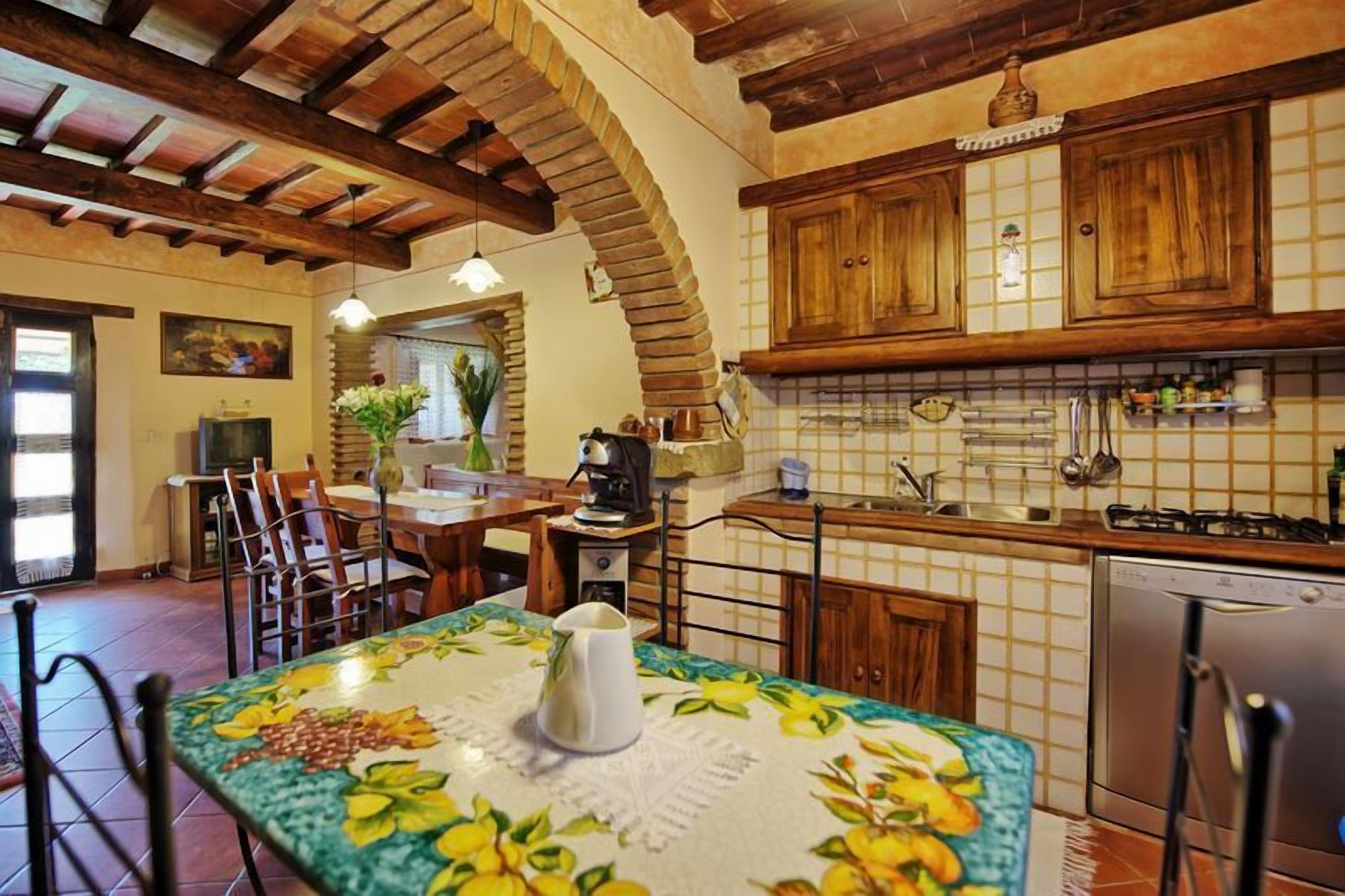 A rustic kitchen with wooden cabinets, a tiled backsplash, and a dining area with a table set for two.