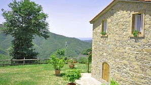 A stone building with a rustic appearance, a wooden door, and a window with a curtain. - Villa Margherita (Cortona)